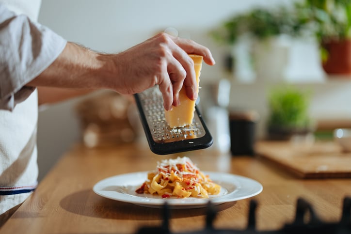 Kaas raspen over een boord met pasta. 