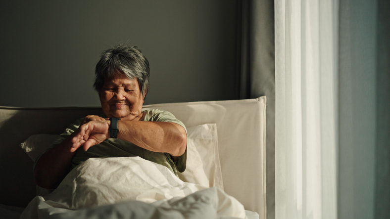 Vrouw in bed kijkend op horloge