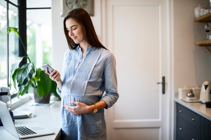 Zwangere vrouw kijkt op haar mobiel 