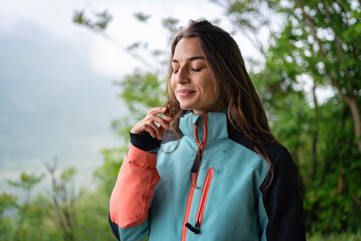 Vrouw staat buiten met eten in haar hand