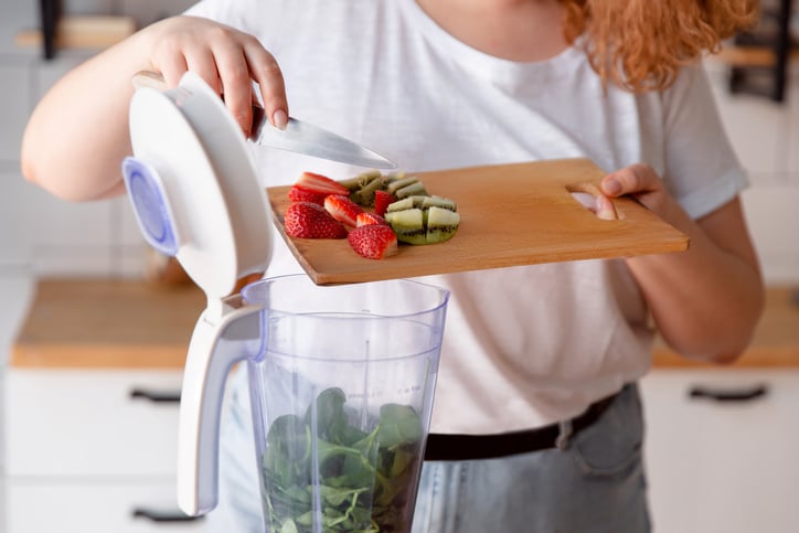 Vrouw doet fruit in de blender