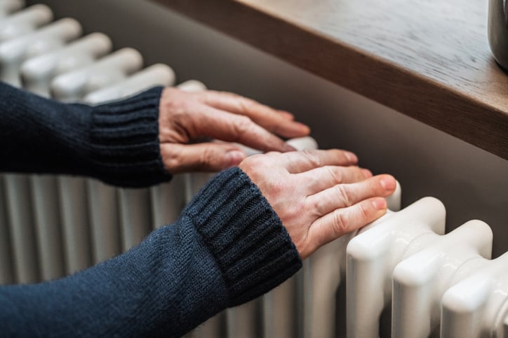 vrouw-warmt-handen-aan-verwarming