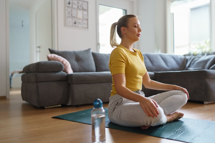 Vrouw aan het mediteren op een yoga mat